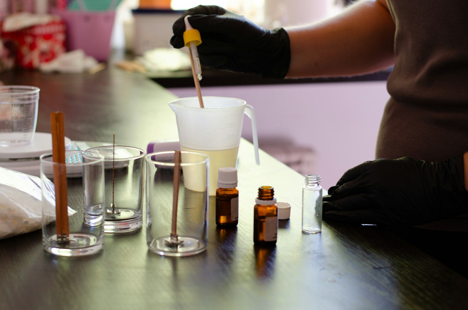 a person in black gloves and gloves pouring liquid into a cup